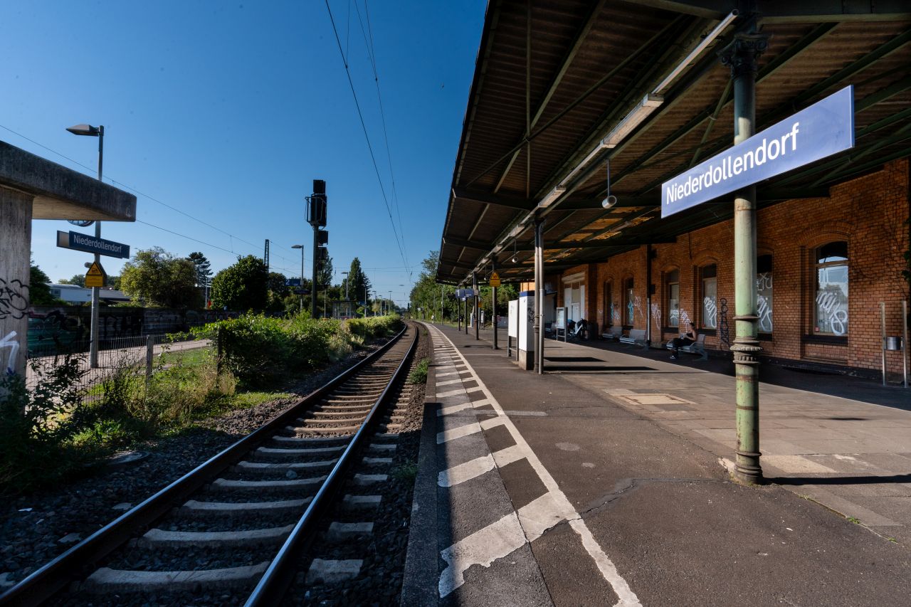 Bahnhofshaus Niederdollendorf an einem Bahnsteig mit überdachtem Bereich und blauem Himmel.