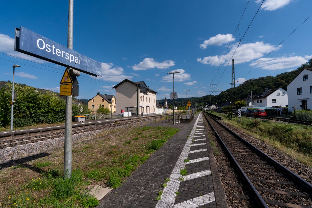 Bahnsteig des Bahnhof Osterspai, mit Blick auf Häuser und grüne Landschaft.